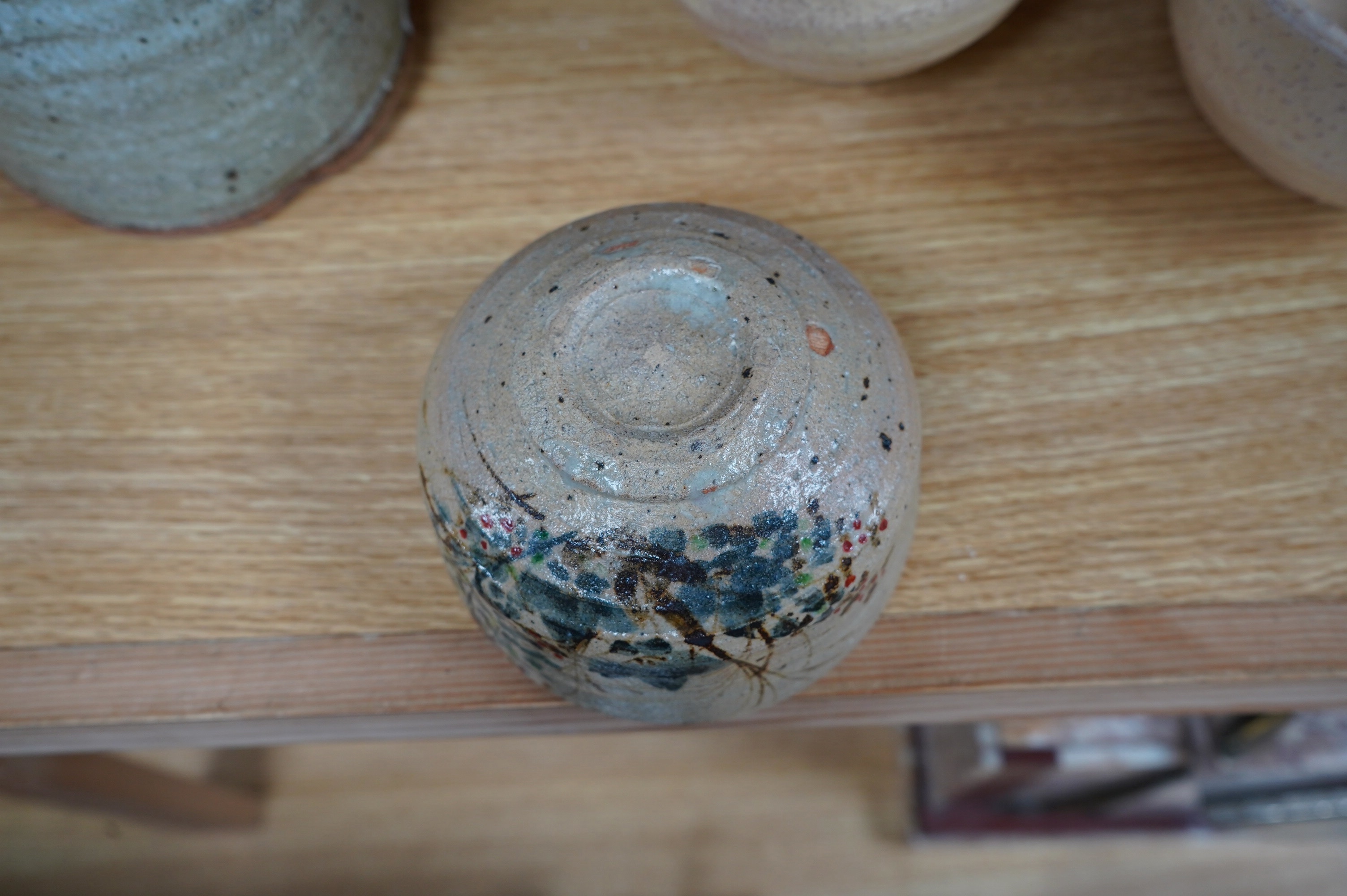 Japanese studio pottery comprising a Nishiyama (Contemporary Japanese School) tea bowl in the Yashichida style decorated with flowers (fitted box), a near pair of Japanese studio pottery cream ground raku bowls (fitted b